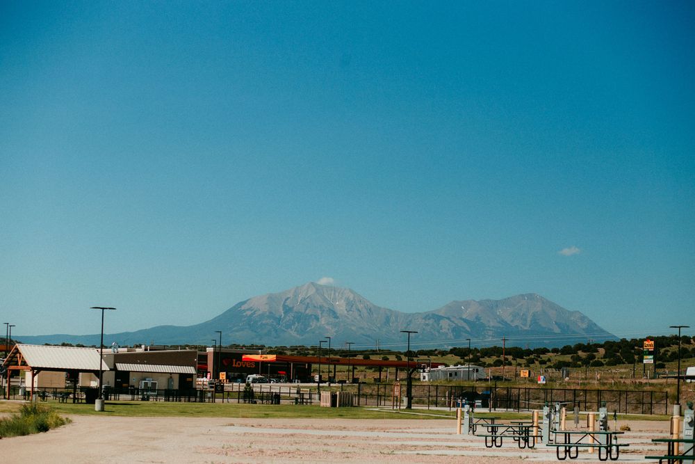 Panoramic mountain landscape view with desert terrain and distant peaks against a clear blue sky.