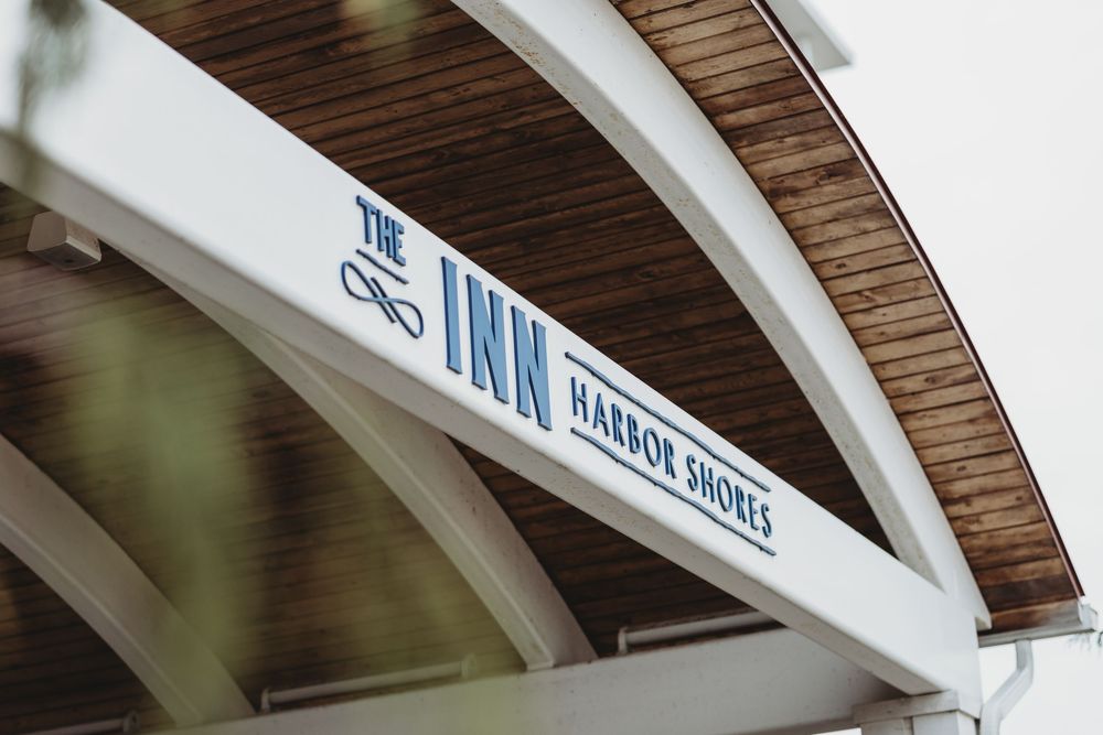 Low-angle view of a wooden arch with 'The Inn' signage in blue lettering against white architectural detail.