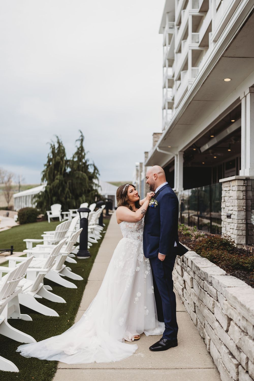 A bride and groom share a romantic moment outside a white stone hotel with a dramatic long train wedding dress.