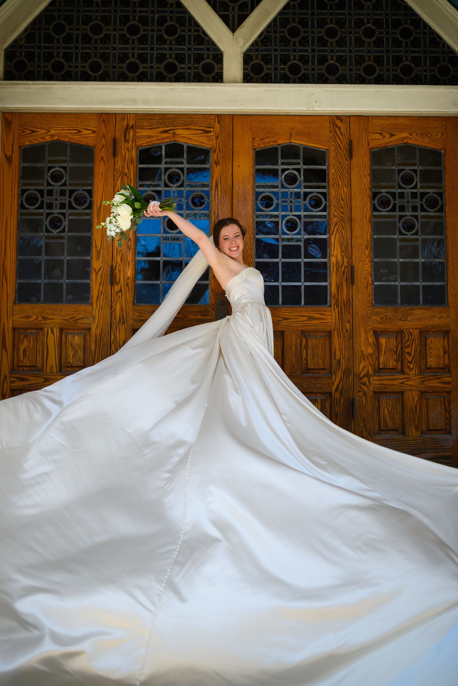 A bride in a flowing white wedding gown spins gracefully, creating a dramatic swirling effect with the dress fabric.