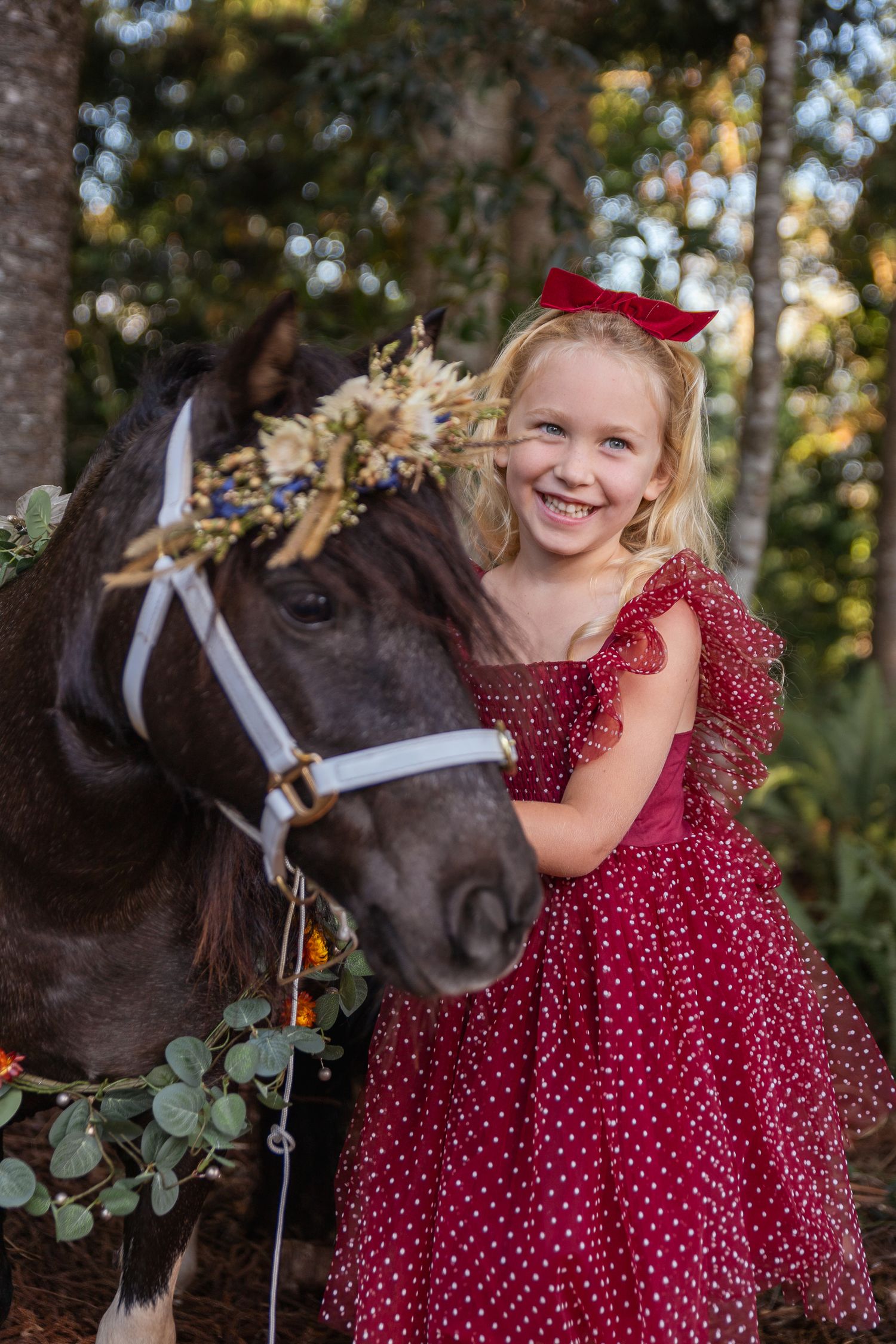 Sweet moment captured with a dark horse wearing floral decorations in an outdoor setting.