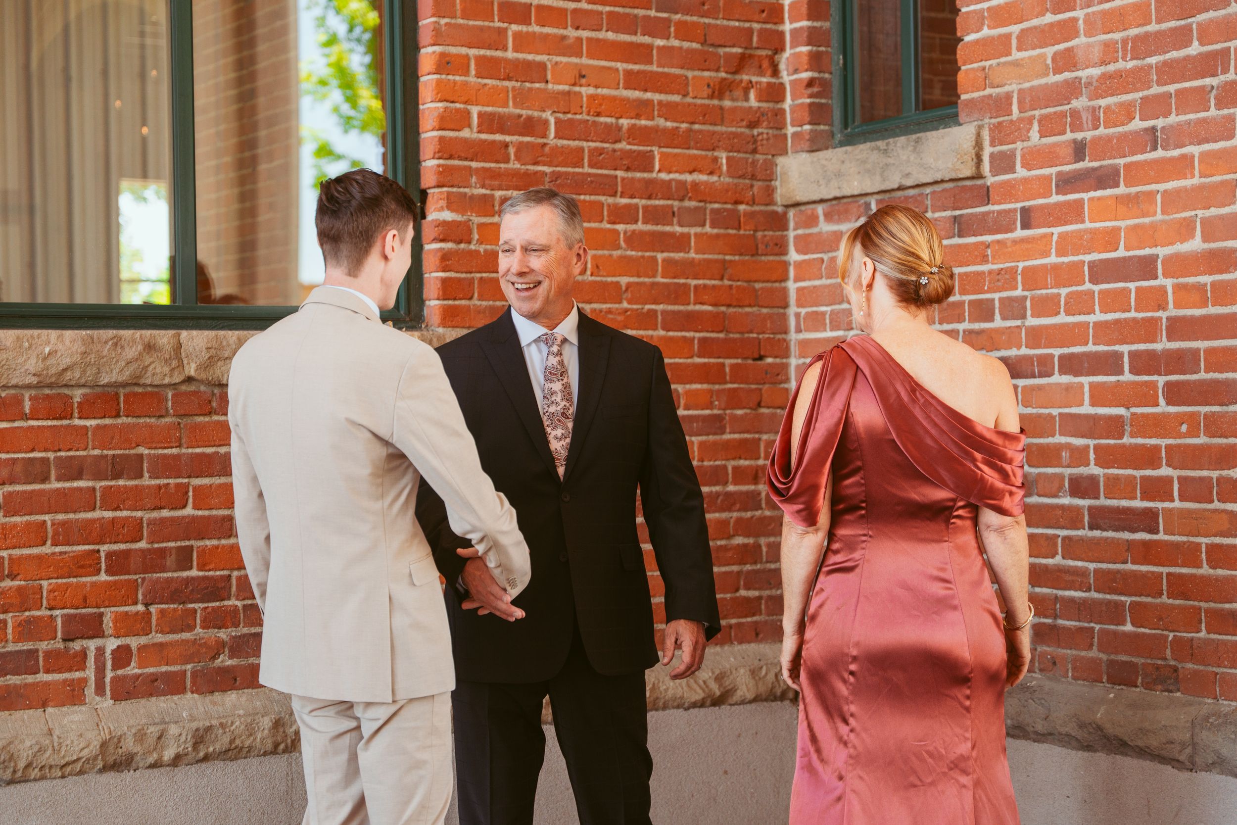Wedding guests gather in front of a rustic brick wall during the celebration.