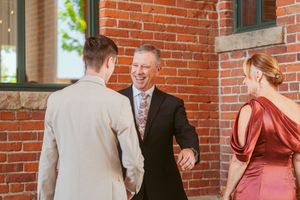 Wedding party members gather and celebrate against a classic brick wall backdrop.