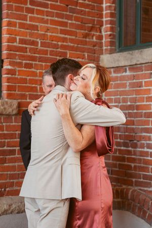 Heartfelt hugs exchanged between wedding guests in formal attire.