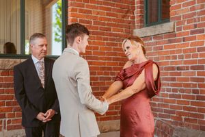 Couple shares intimate moment with officiant outside historic brick building.
