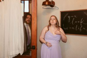 Wedding party members share candid moments together in a venue with exposed brick and chalkboard walls.