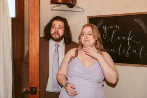 A couple shares an emotional moment in front of a chalkboard at their wedding celebration.
