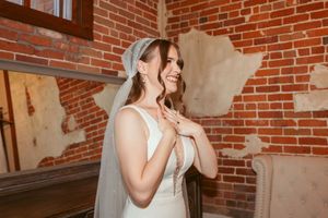 A candid moment at a brick-walled wedding venue with a figure in white bridal attire.