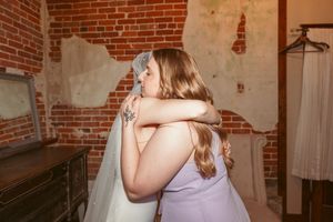 Emotional embrace captured in a rustic venue with exposed brick walls and vintage decor.