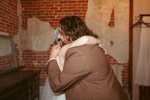An emotional wedding moment captured against exposed brick walls.