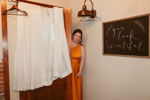 Two people getting ready in a rustic room with brick walls and sheer white curtains.