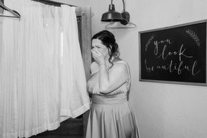 Emotional moment captured in black and white as bridesmaid views wedding dress.
