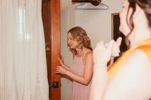 Bridesmaid in soft pink dress reacts to seeing wedding gown.