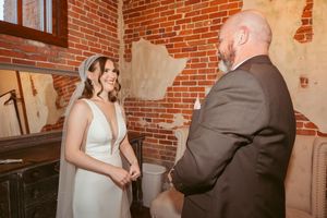 A joyful conversation moment between wedding participants in an industrial brick venue.