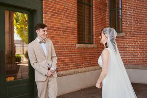 Bride and groom share their first look outside brick church building.