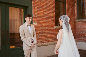 A modern wedding ceremony takes place against exposed brick walls in an indoor venue.