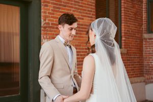 Intimate first look moment between bride and groom against brick exterior.