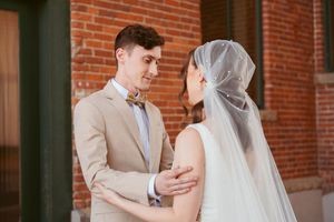 A wedding couple shares an intimate moment against a rustic brick wall backdrop during their special day.