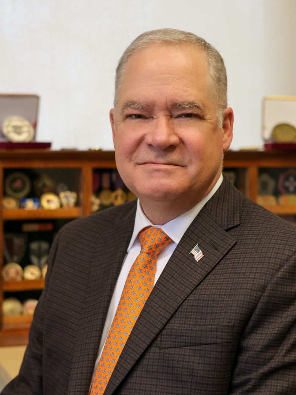 A side-by-side sequence of similar portraits showing someone in a dark suit with an orange tie in front of bookshelves.