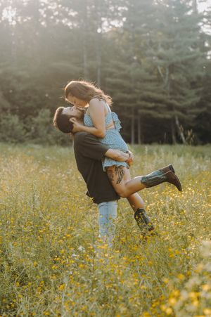 Joyful couple dancing and spinning in a field of yellow wildflowers.