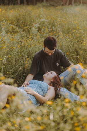 Couple lying together in a summer meadow filled with yellow flowers.