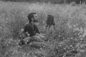 Black and white photo of a couple sharing an intimate moment in a wildflower field.