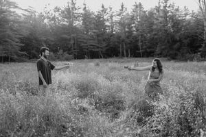 Black and white panoramic view of a couple in a natural meadow setting.