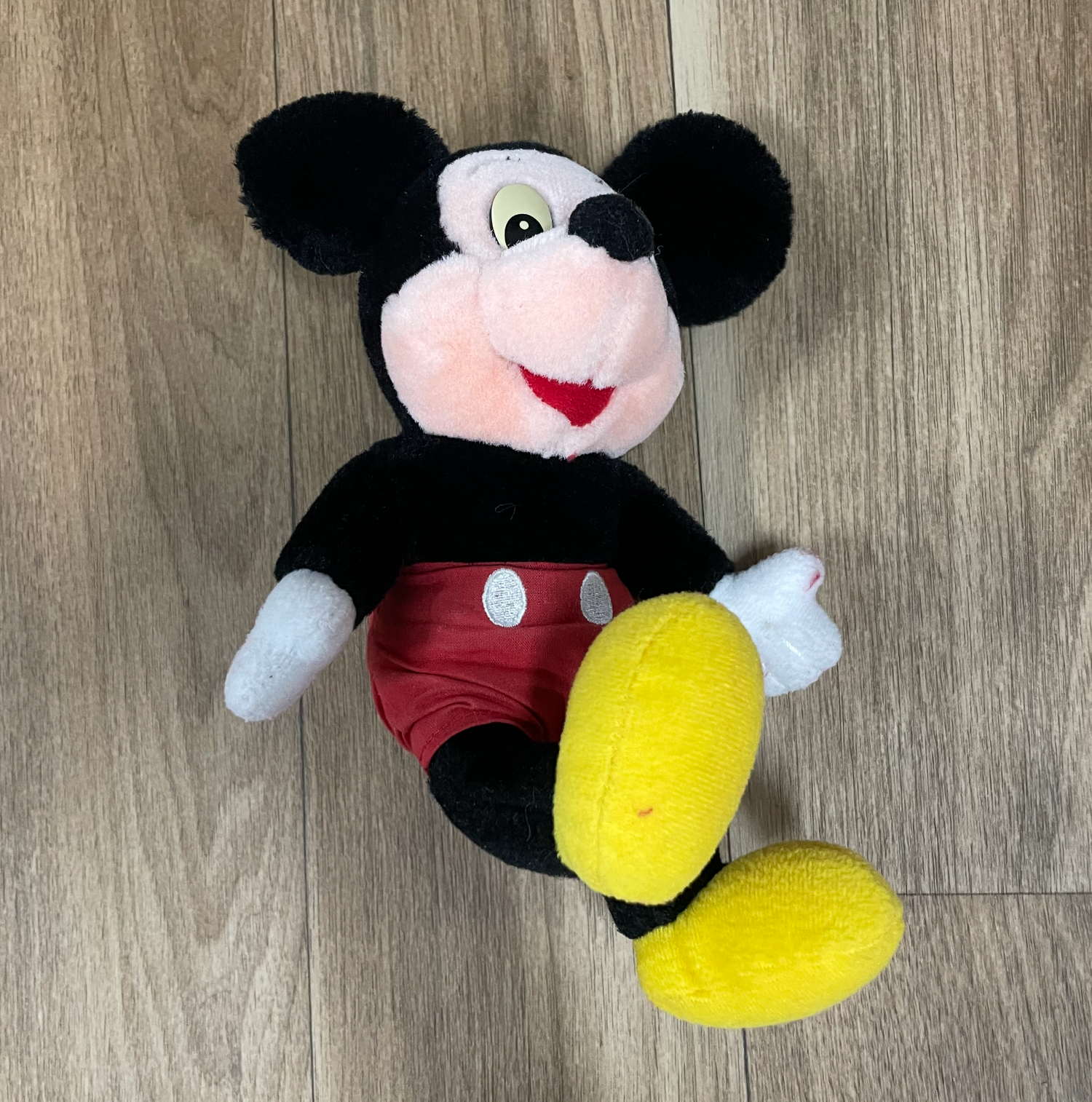 Mickey Mouse plush toys displayed on a wooden floor showing different poses and angles.