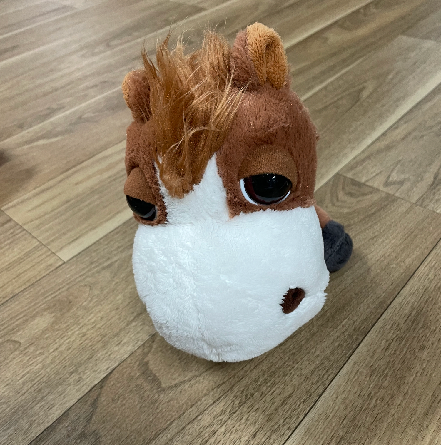 Brown and white hamster plush toys lined up on hardwood flooring.