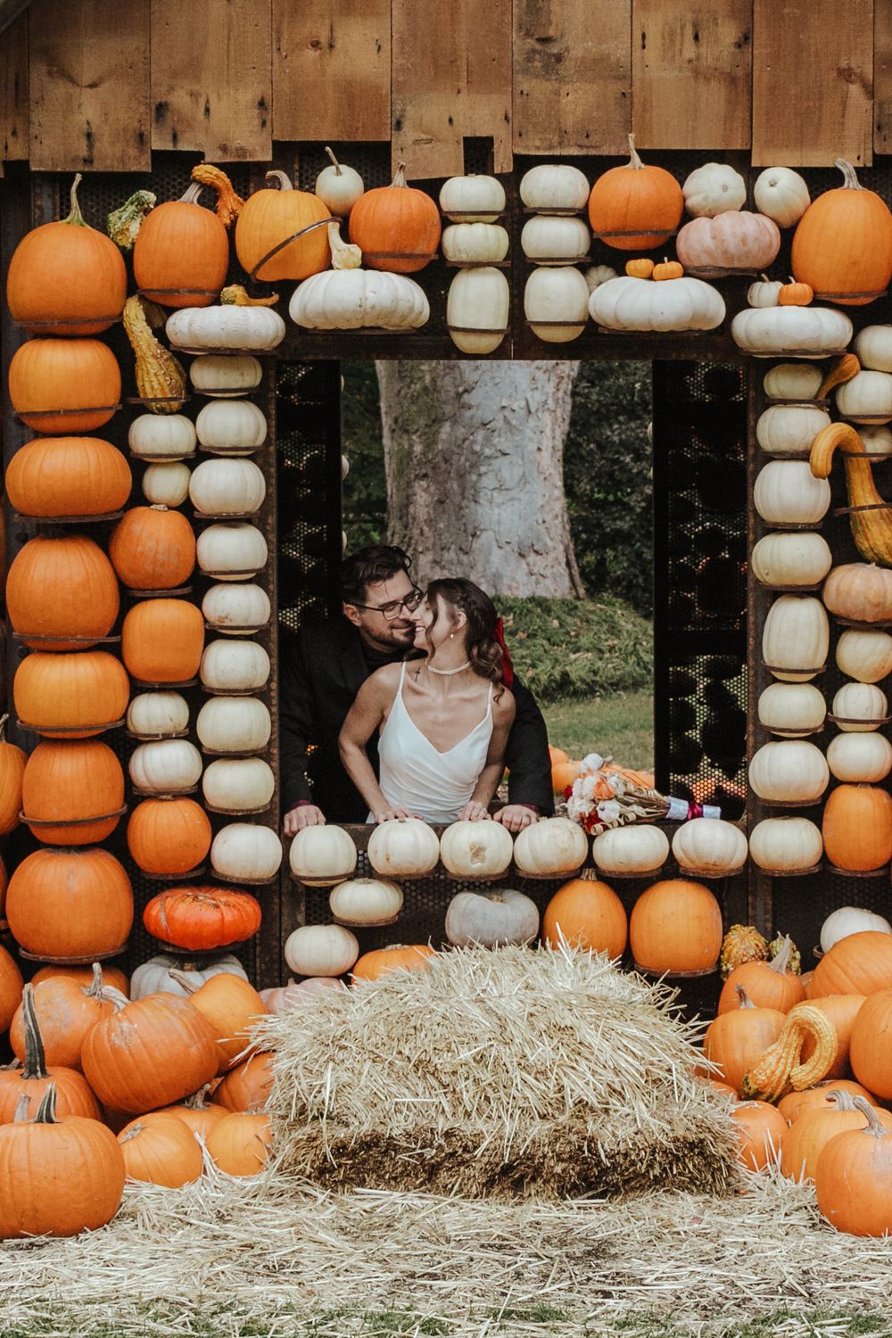 A festive autumn pumpkin patch display with white and orange pumpkins arranged around hay bales for seasonal photography.