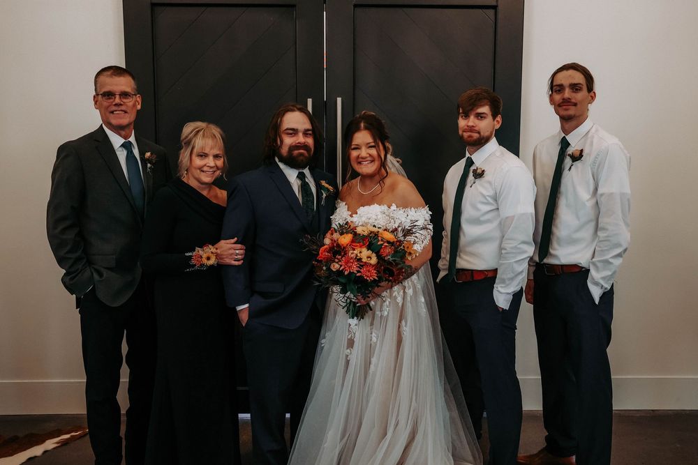 Wedding party members arranged in formal line against minimalist dark backdrop.