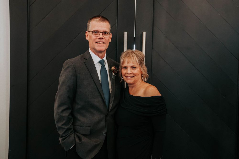Business professionals in formal attire stand in front of dark wall at corporate event setting.