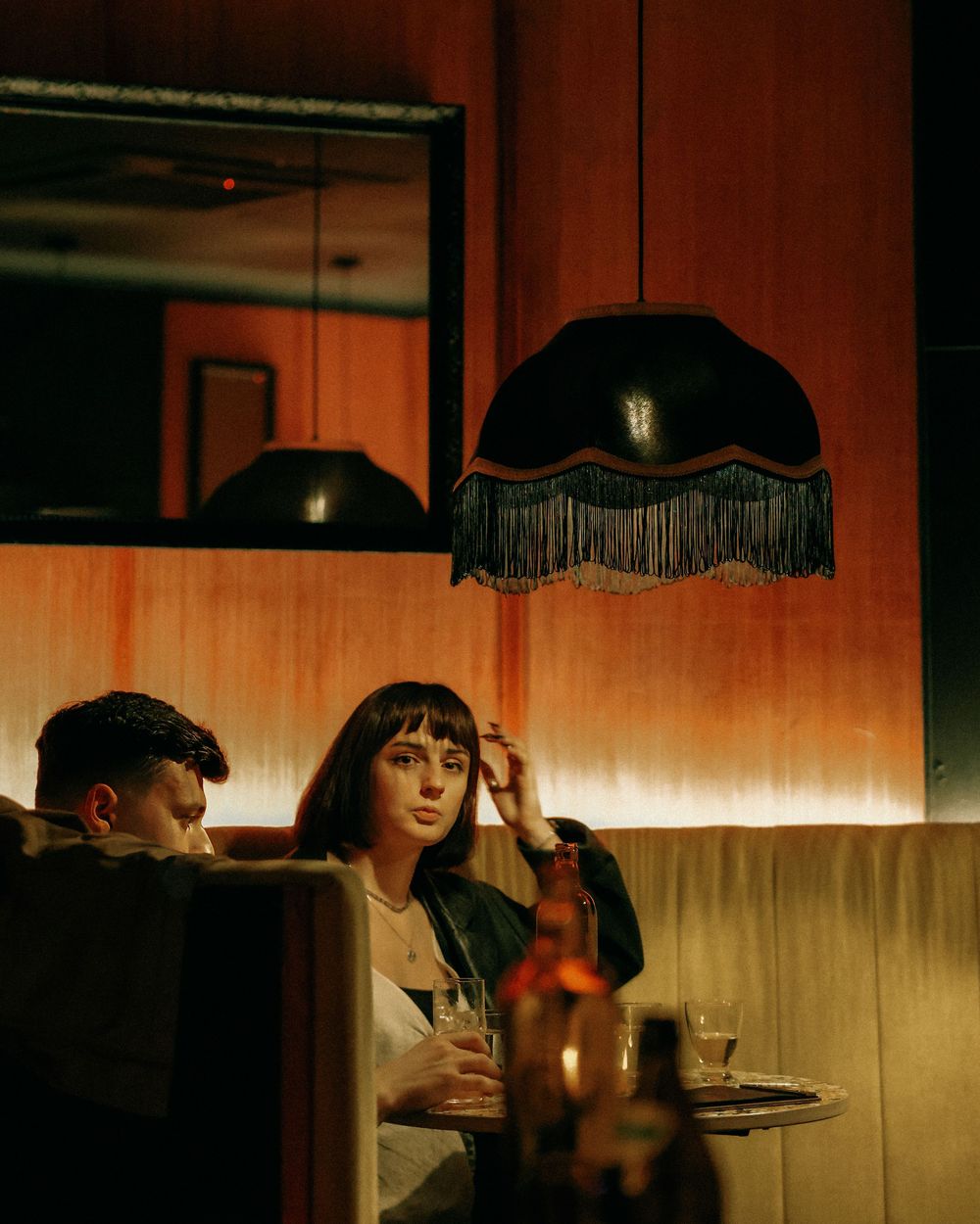 Moody restaurant scene with vintage black fringed pendant lamps and warm lighting.