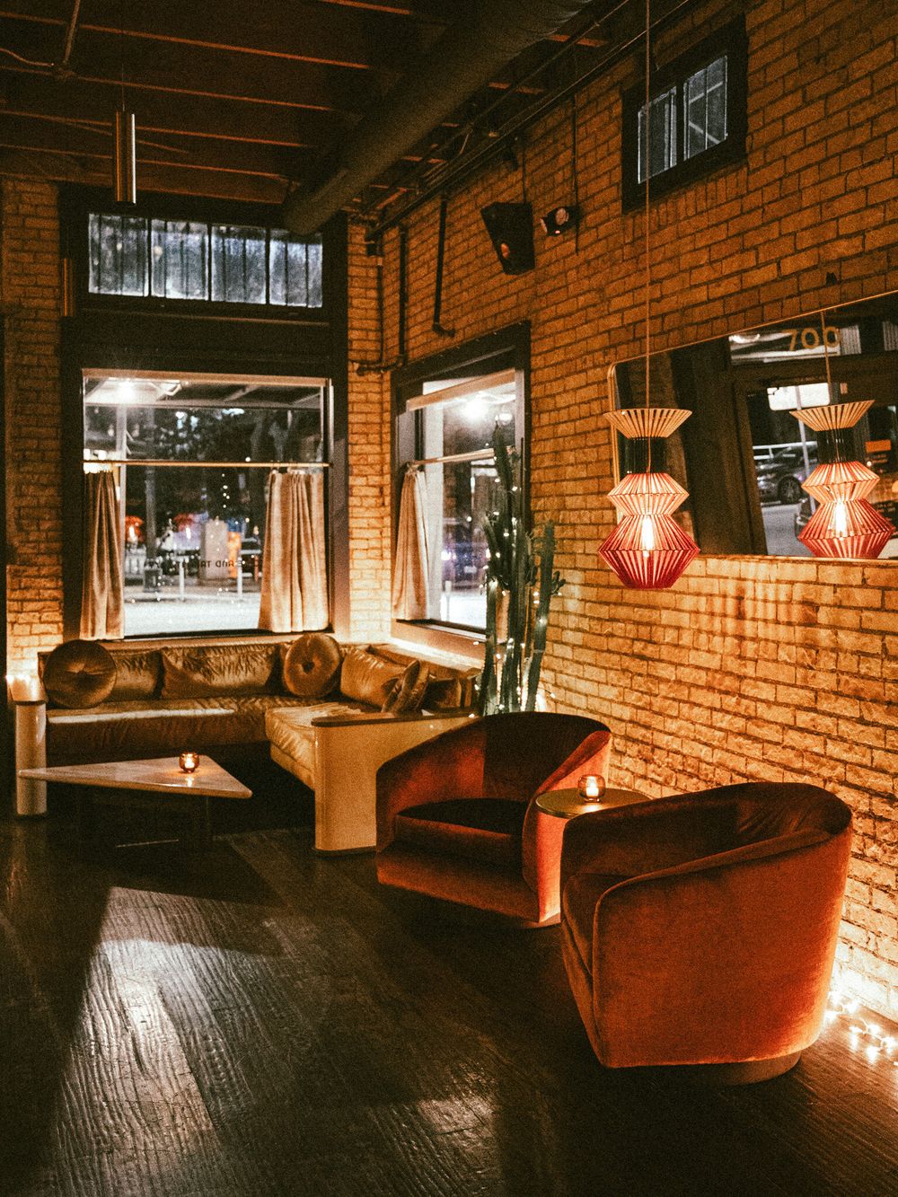 Industrial-style lounge with exposed brick walls, red lighting, and plush leather seating.