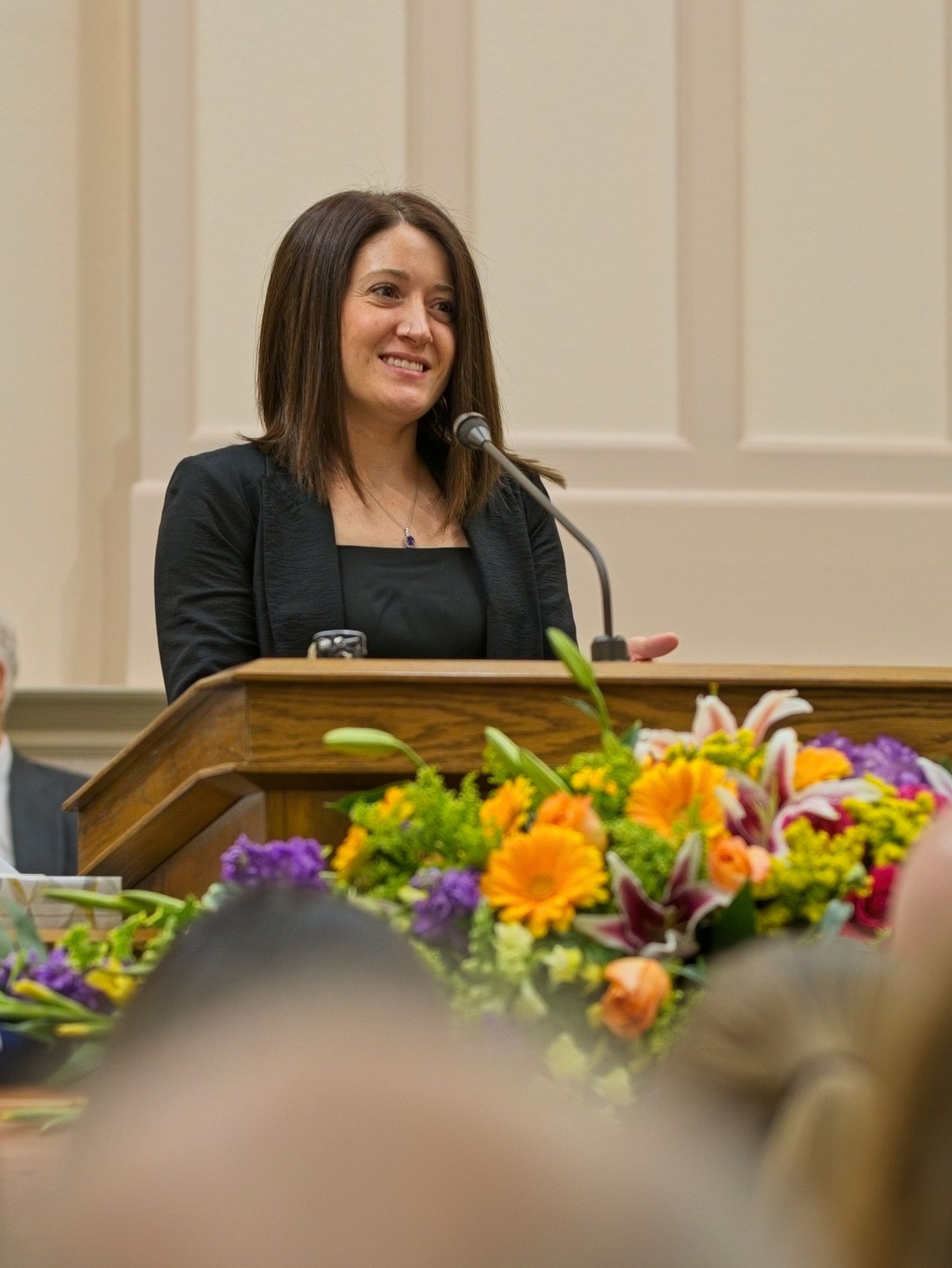A woman stands at the pulpit sharing stories of her father.