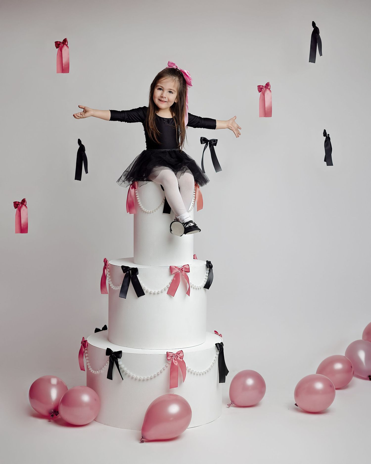 Creative portrait on tiered white display with pink and black ribbon decorations.