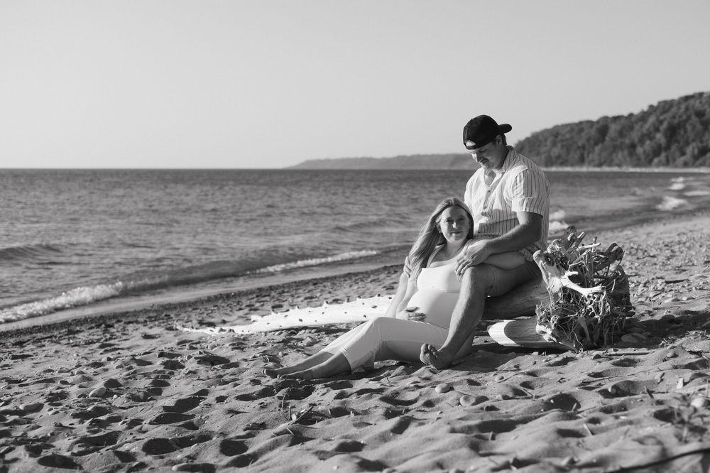 A black and white montage sequence shows two people relaxing on a sandy beach near the ocean shore.