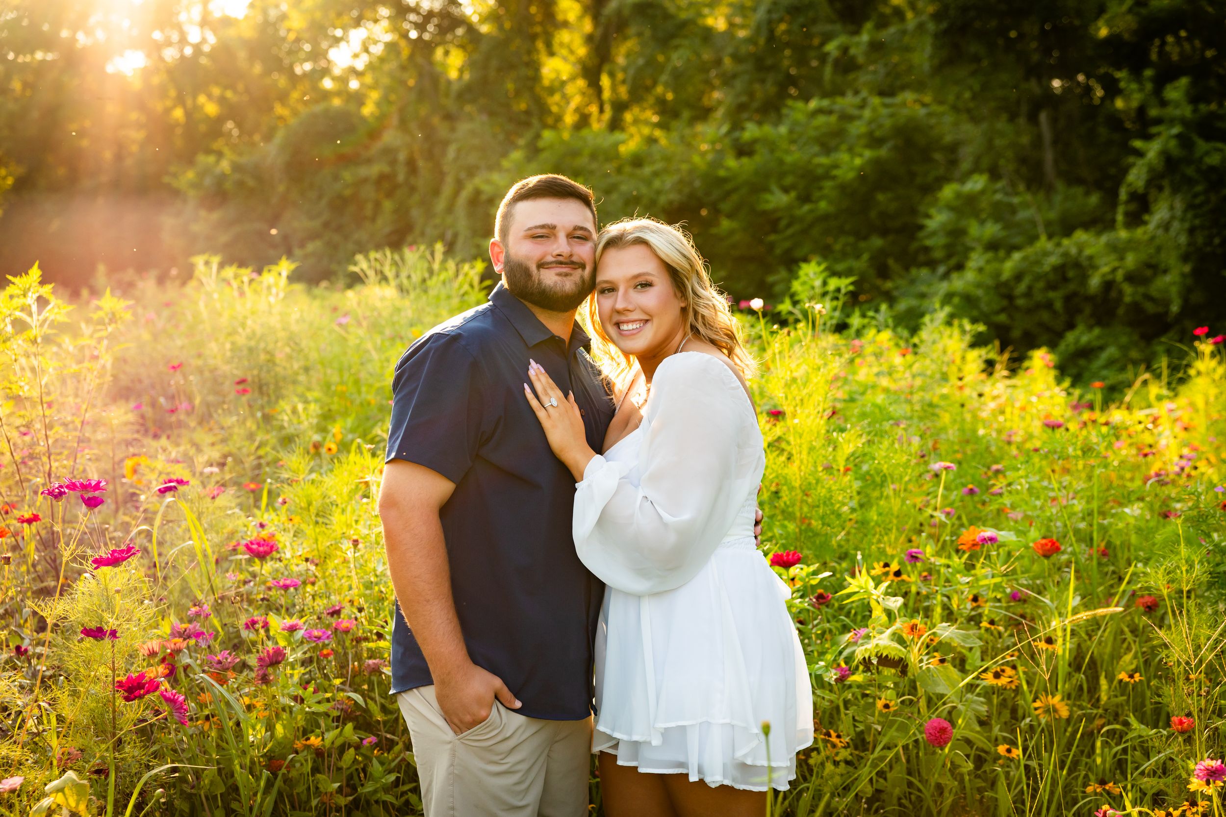 Romantic couple shares tender moments in a sunlit wildflower meadow during golden hour sunset photography session.