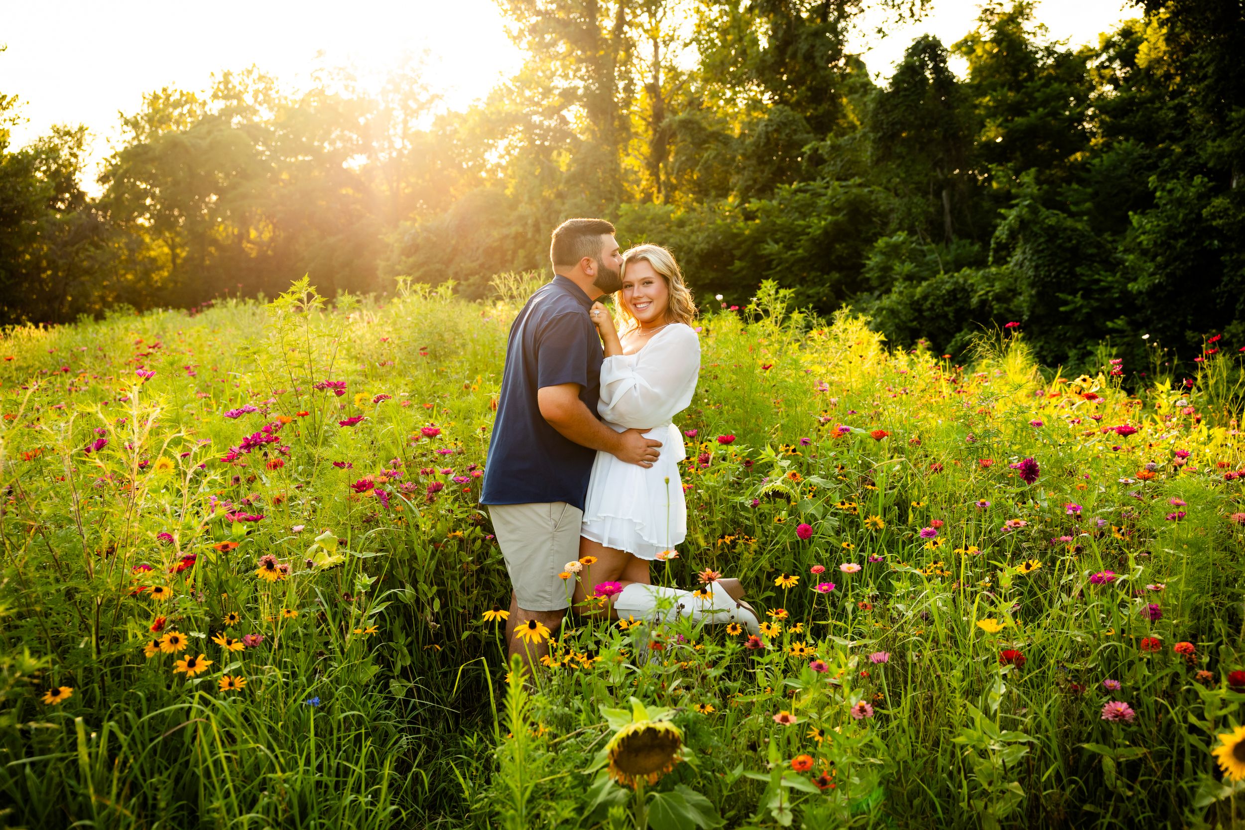 A couple enjoys a romantic sunset moment in a vibrant wildflower meadow on a warm summer evening.