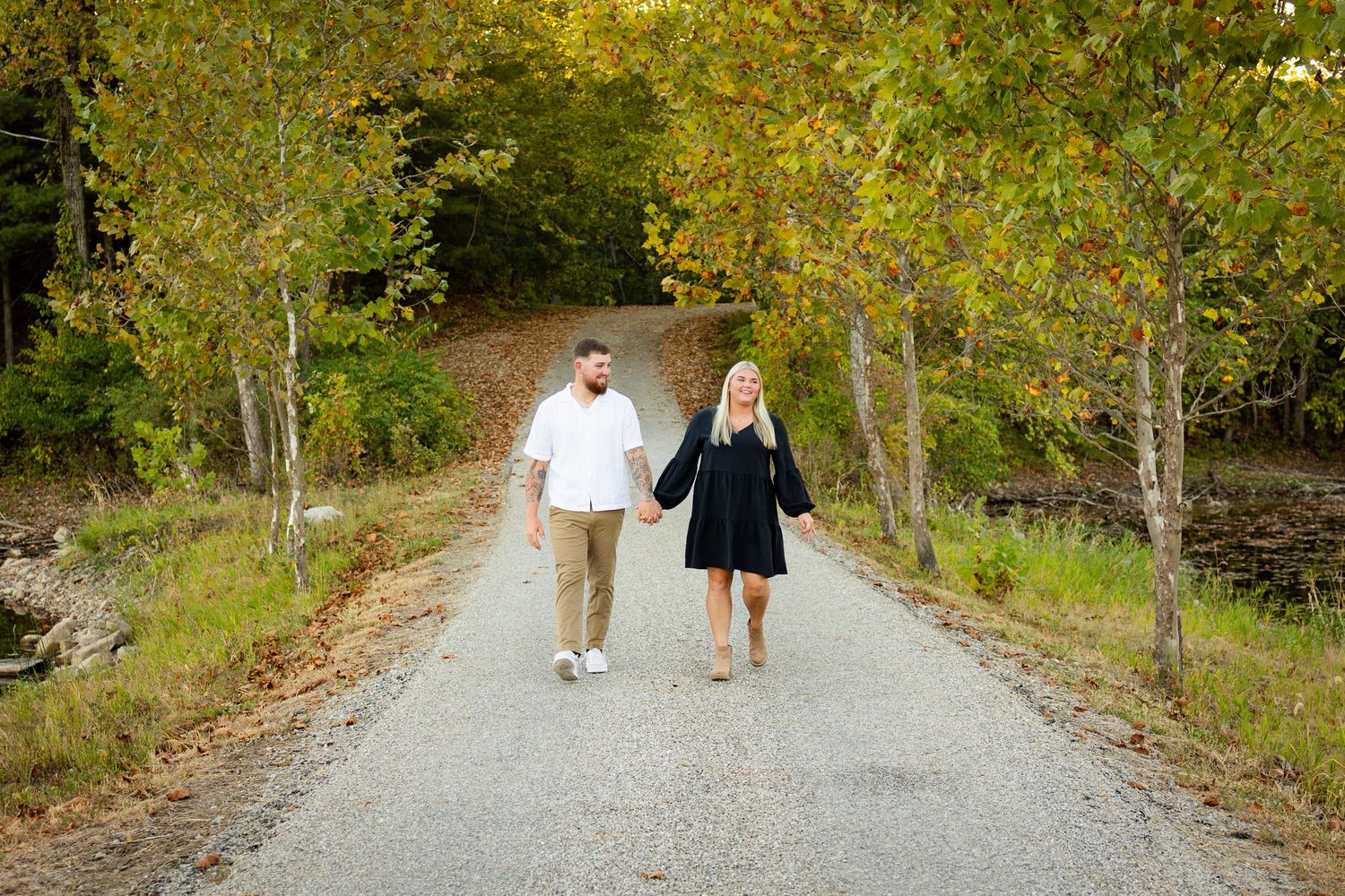 A family walks along a tree-lined path on a sunny autumn afternoon while holding hands and enjoying nature together.