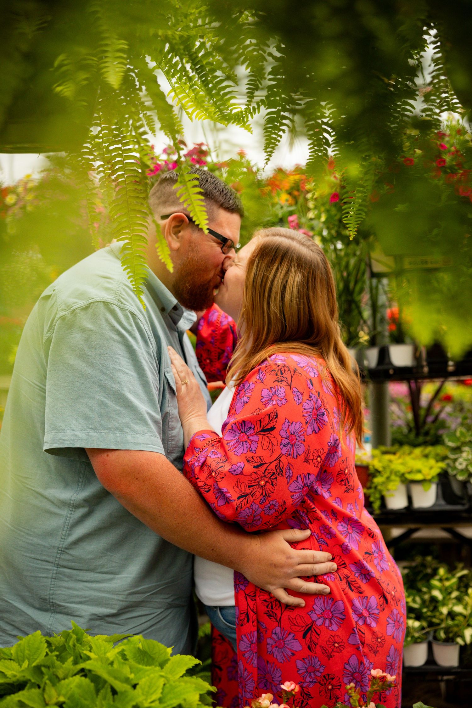 A romantic garden scene with greenery and ferns providing a lush backdrop among colorful flowers and plant stands.