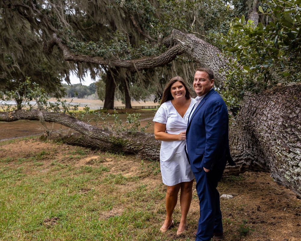 A romantic outdoor photo session under a large oak tree in a natural park setting.