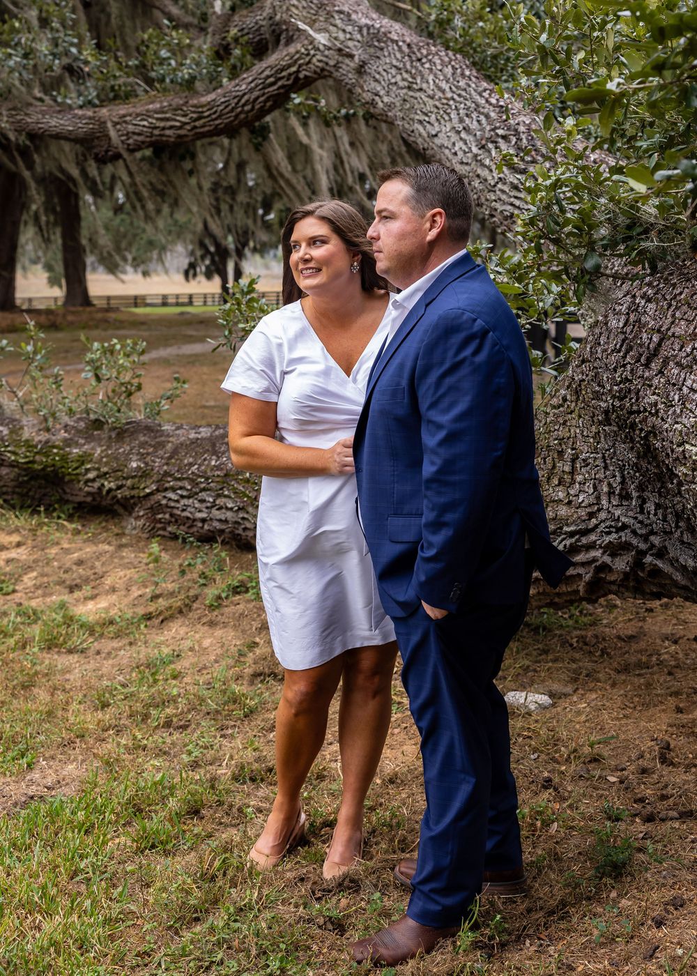 Two people sharing laughter and embraces near a massive oak tree.