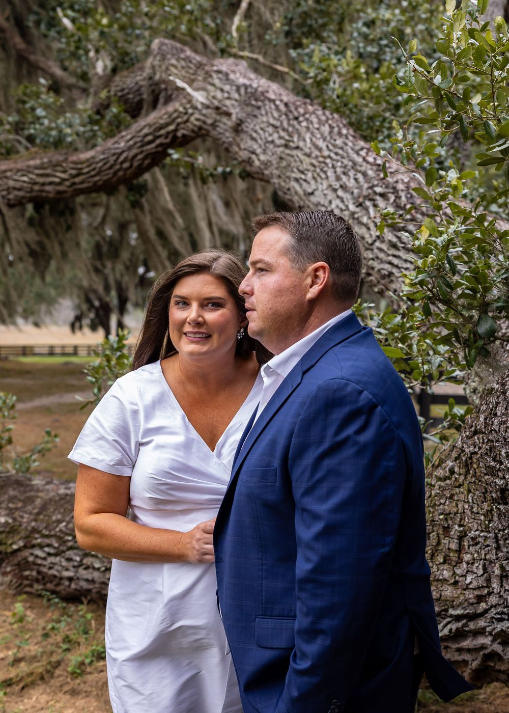 Candid moments captured between a couple near a large tree trunk in an outdoor setting.