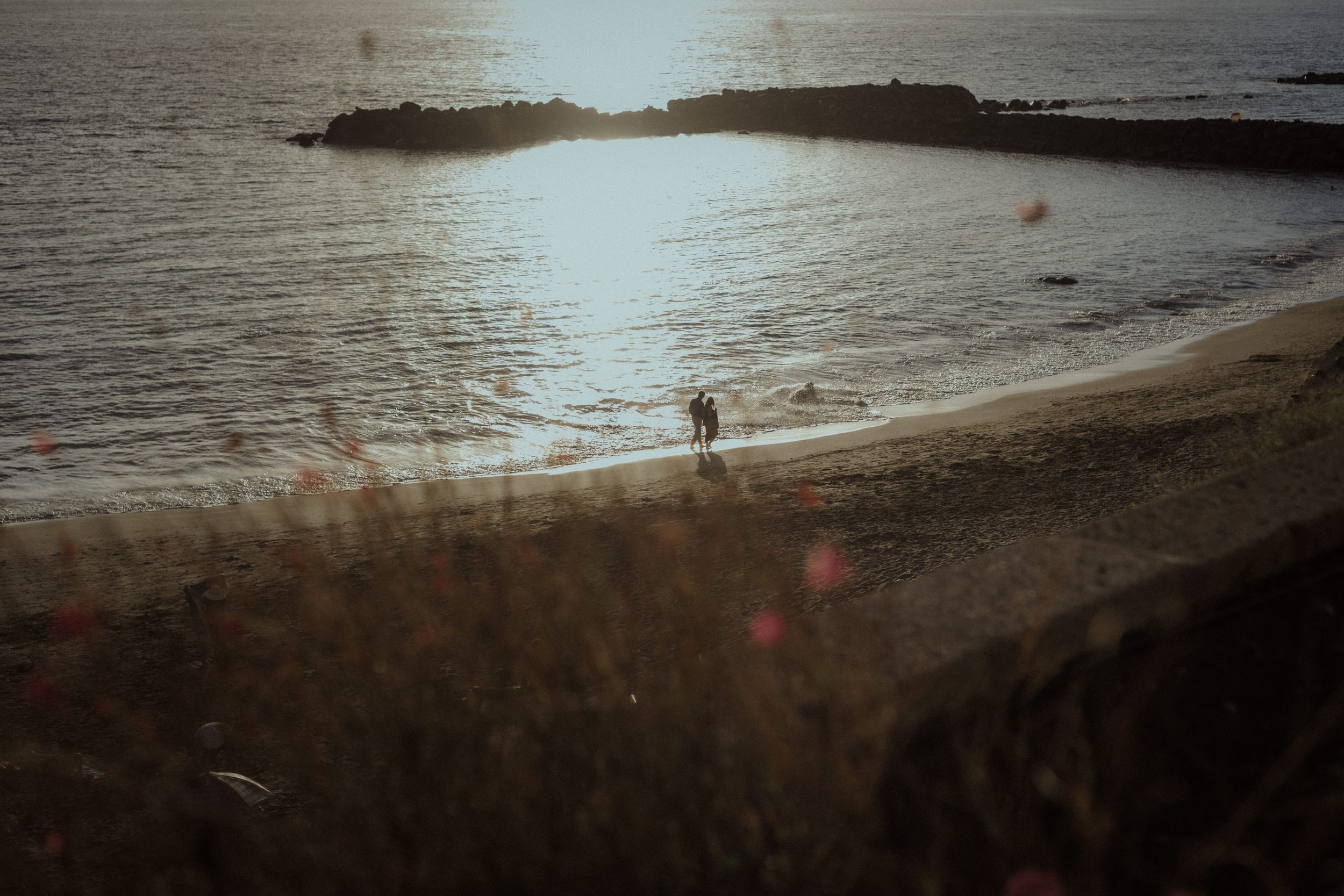 Tranquil beach shoreline at sunset with gentle waves lapping against the sand.