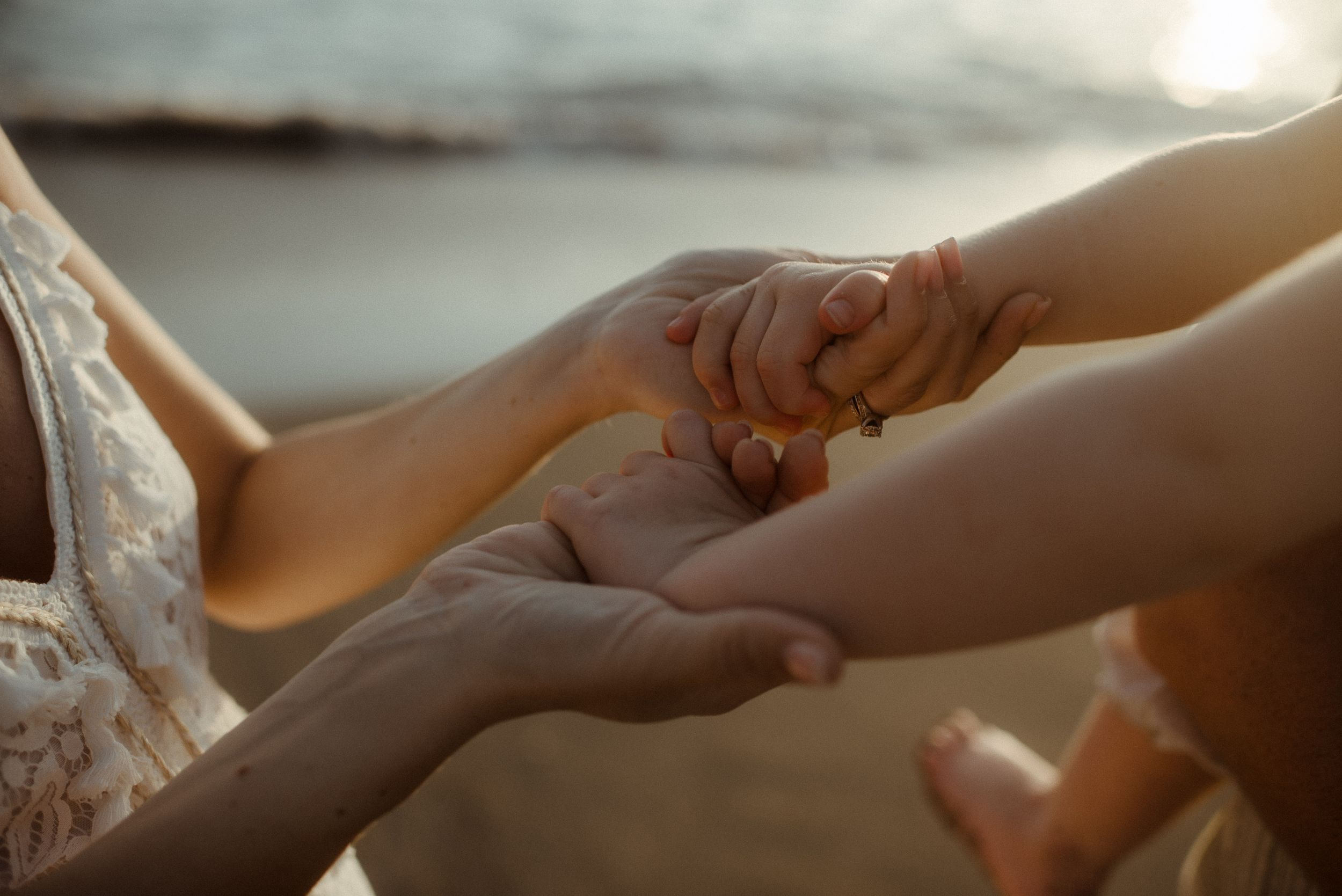 Close-up shot of hands gently clasped together against a soft, warm background at Playa del Duque.