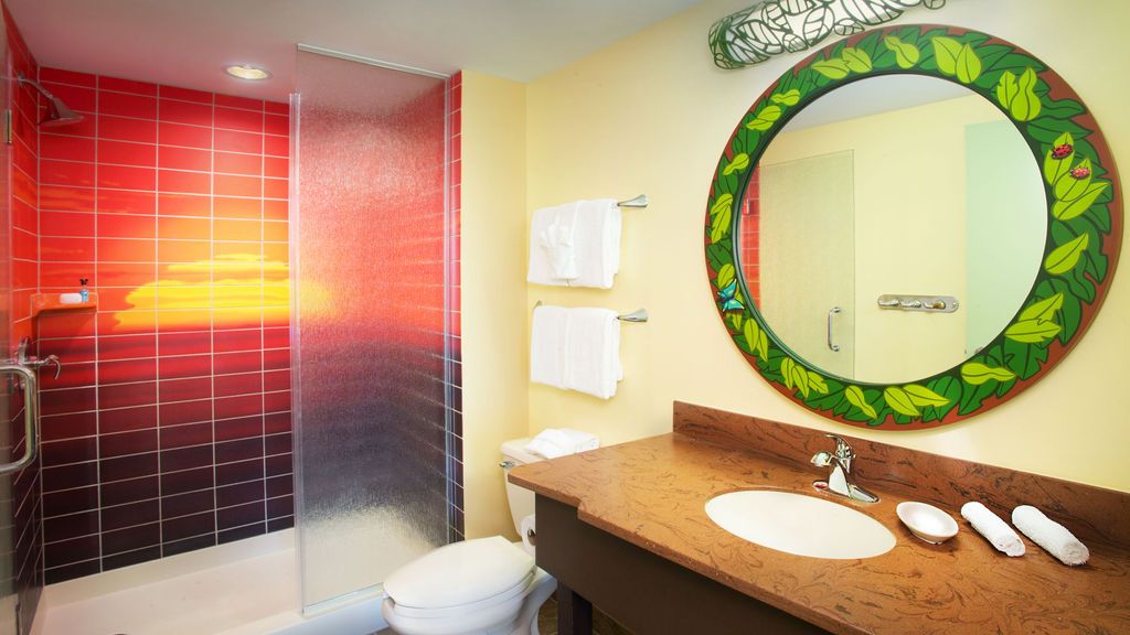 Modern bathroom with red gradient tile shower and decorative green circular mirror.