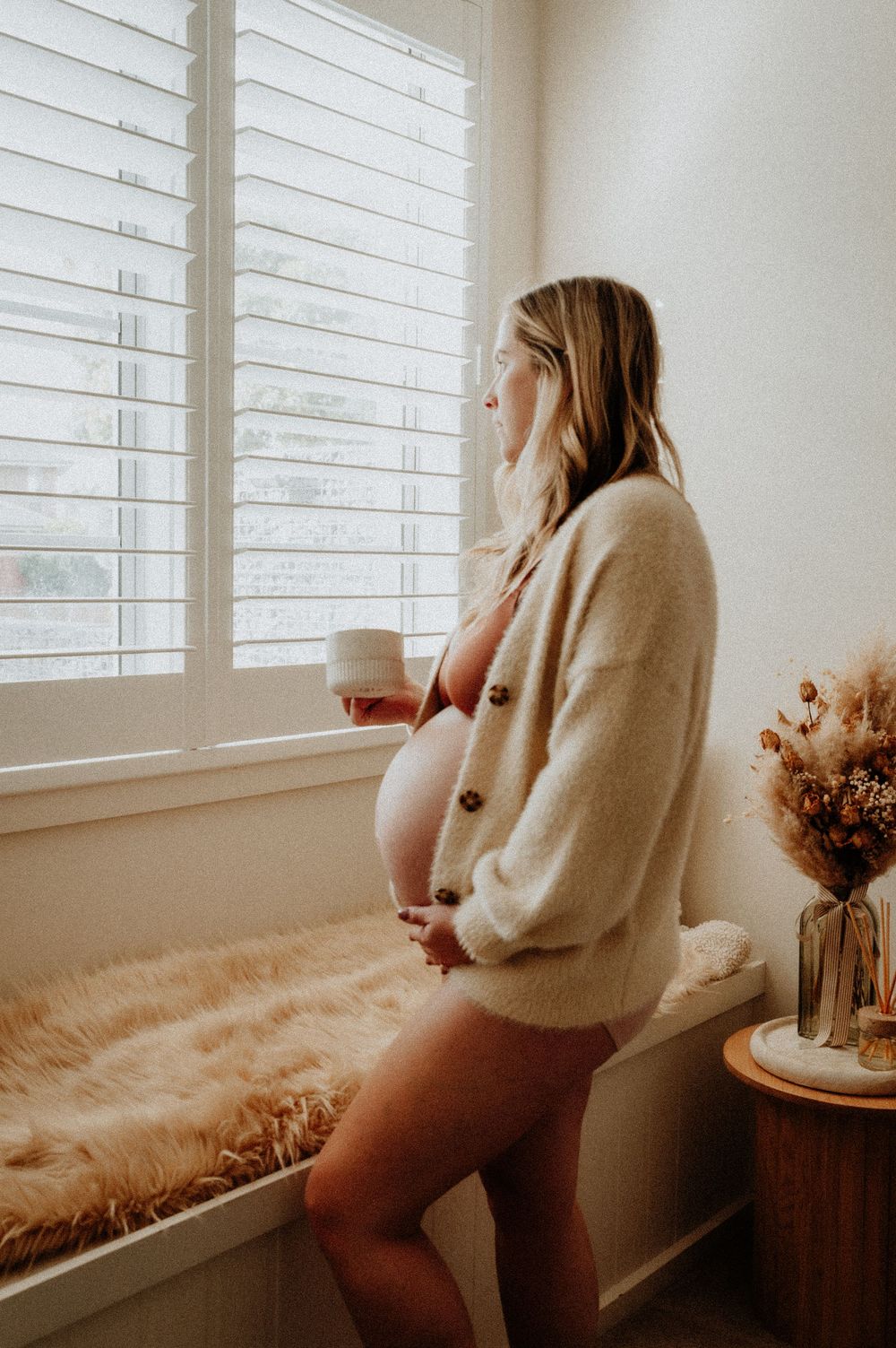 Side view of pregnant woman gazing through window while standing in cozy interior setting.
Altona Family Photographer Melbourne