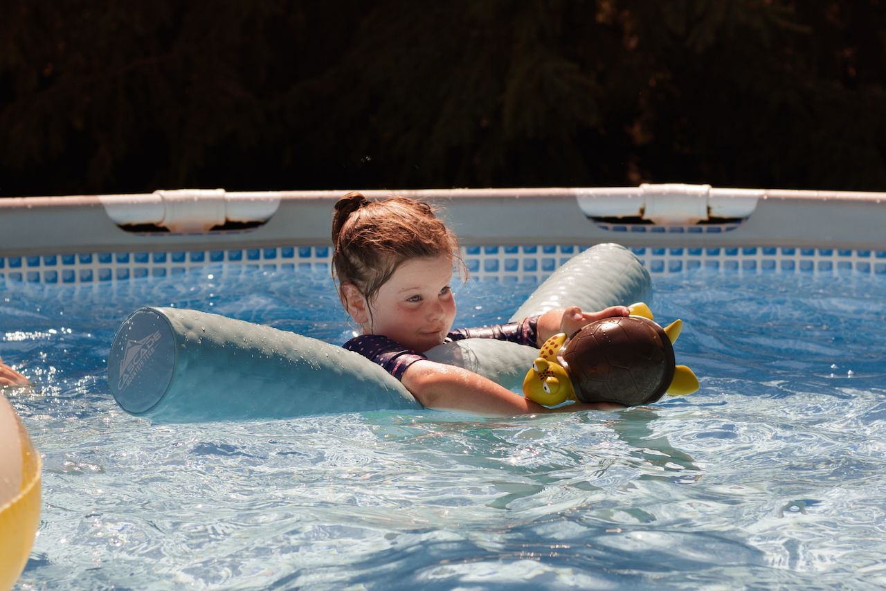 Little girl in swimming pool making a silly face - South Lyon, Michigan family photographer.