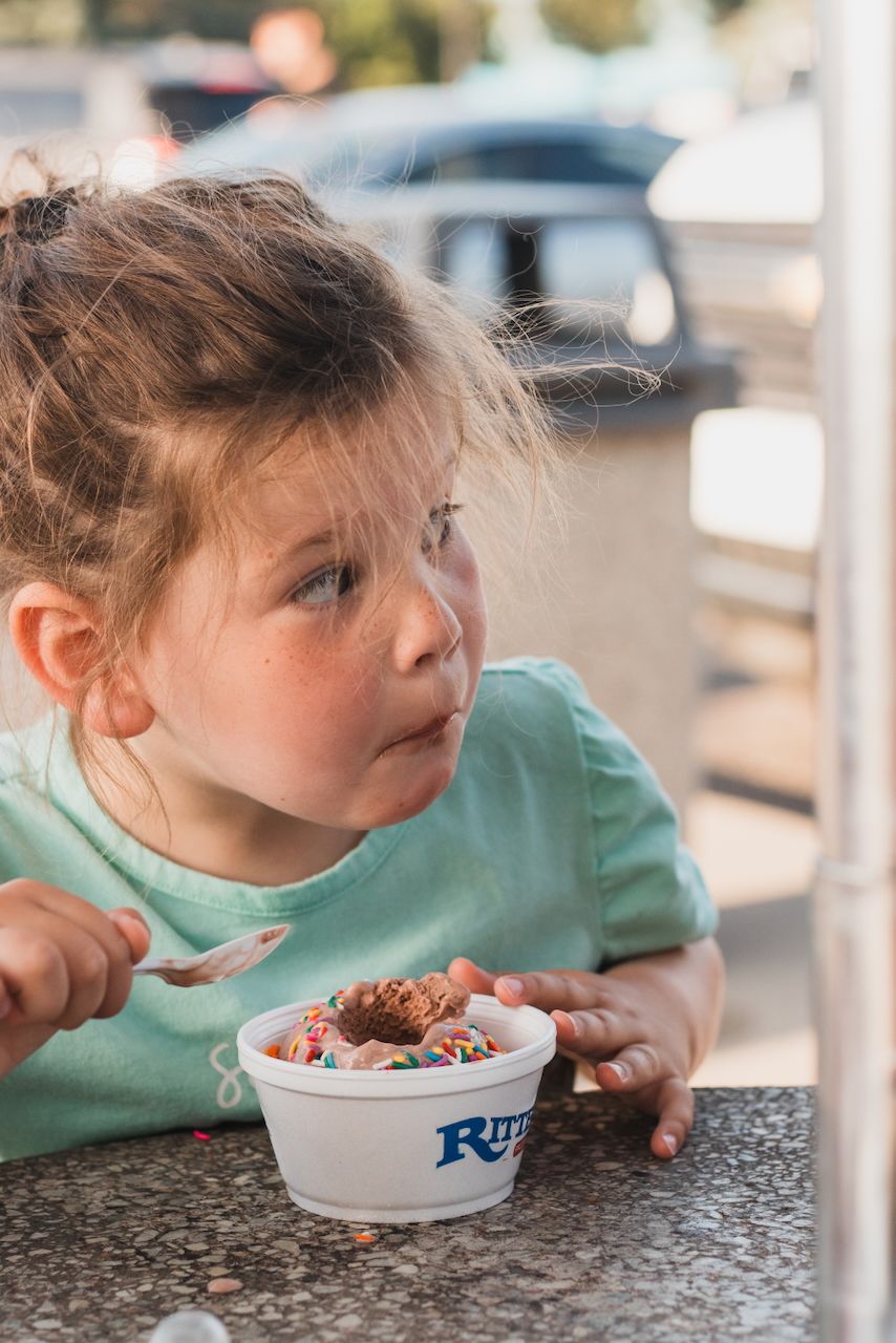 Little girl eating ice cream with sprinkles - lifestyle family photographer near Brighton, Michigan.